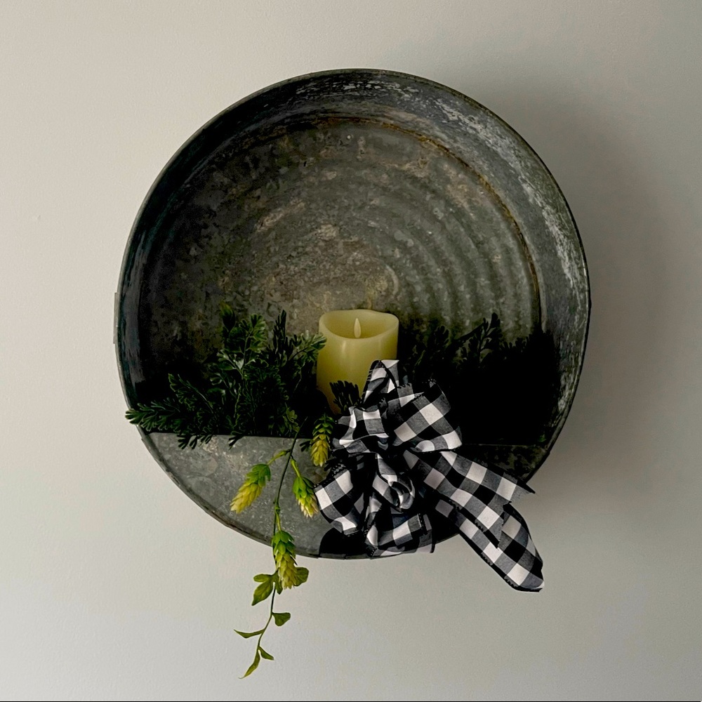 Rustic metal oil pan wall decor with candle.